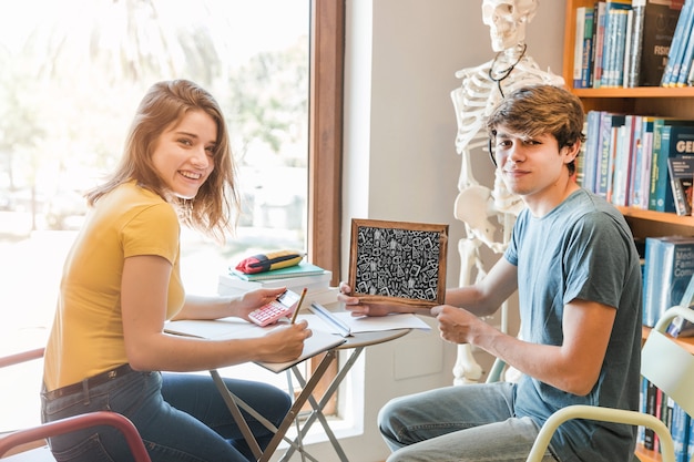 Young couple with slate mockup in library