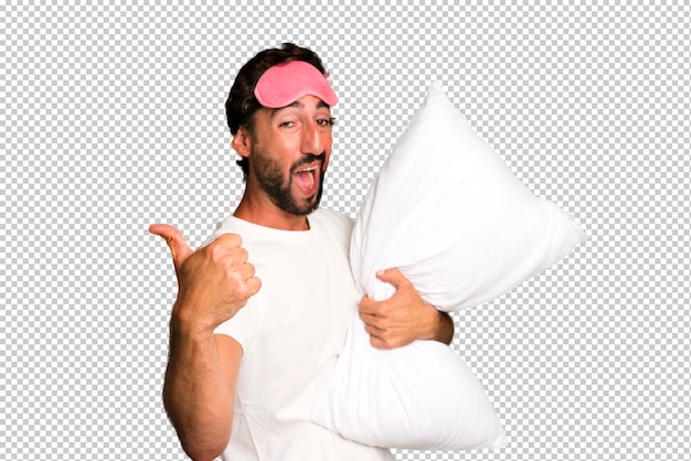 PSD young crazy bearded and expressive man wearing pajamas and eye mask and with a pillow