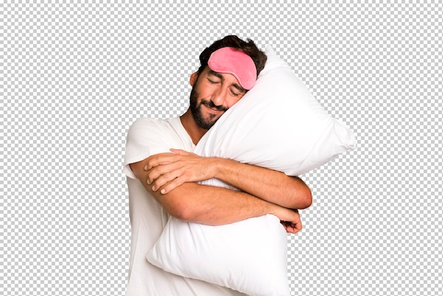 Young crazy bearded and expressive man wearing pajamas and eye mask and with a pillow