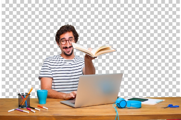 Young crazy graphic designer on a desk with a laptop and with a book