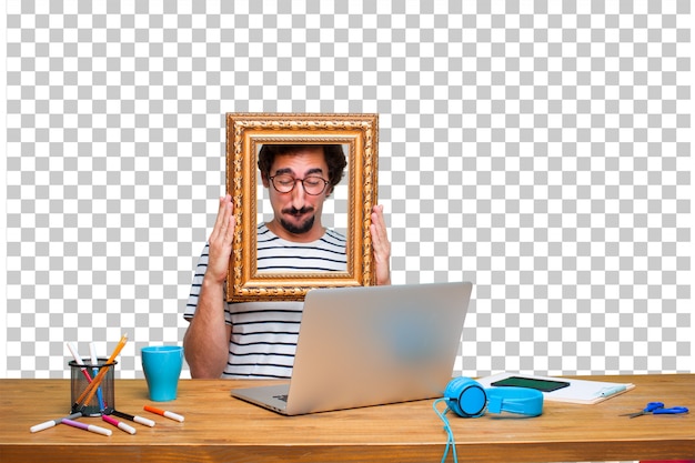 Young crazy graphic designer on a desk with a laptop and with a frame