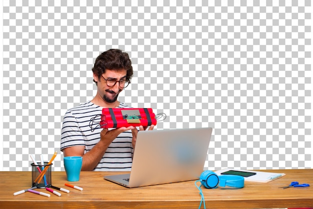 Молодой безумный графический дизайнер на столе с ноутбуком и с динамитной бомбой