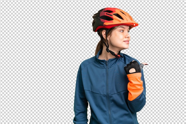 Young cyclist girl over isolated chroma key background pointing to the side to present a product
