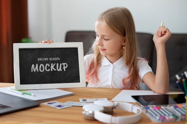 Young girl using small blackboard for online courses