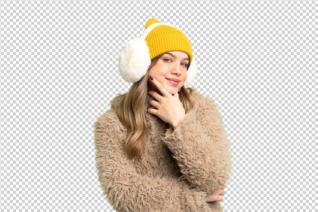 Young girl wearing winter muffs over isolated chroma key background smiling