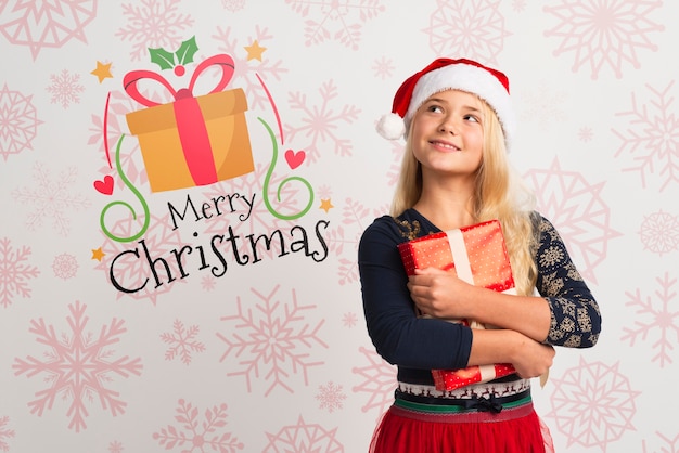 Young girl with santa hat holding gift