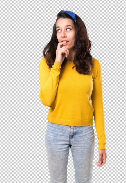 Young girl with yellow sweater and blue bandana on her head having doubts