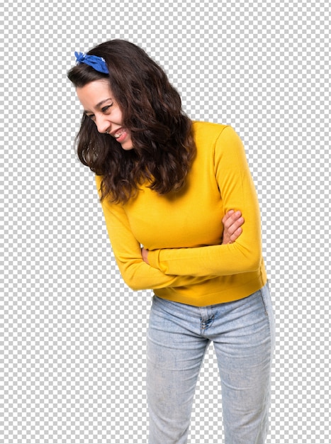 Young girl with yellow sweater and blue bandana on her head keeping the arms crossed while smiling