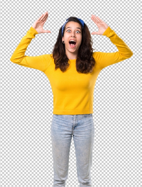 黄色のセーターと驚きの彼女の頭の上に青い帯状の若い女の子