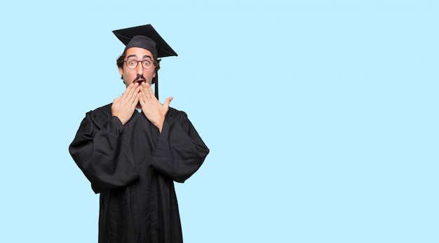 PSD young graduated man covering mouth with hand with a gesture of surprise