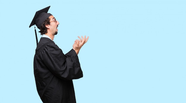 Young graduated man looking stressed and frustrated, holding both hands open in front