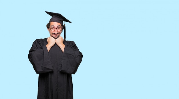 young graduated man with a happy surprised expression, eyes wide open and broad smile
