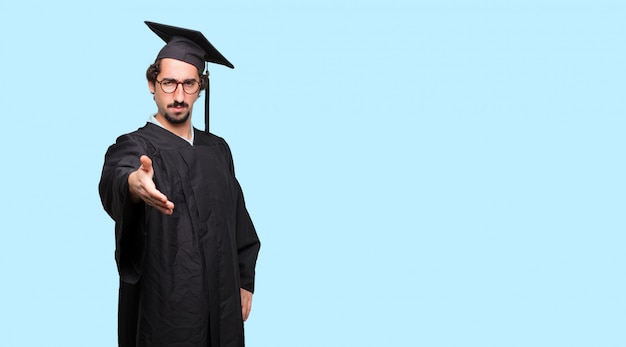 Young graduated man with a serious, confident, proud and stern expression offering a handshake