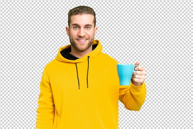 孤立した背景に一杯のコーヒーを保持している若いハンサムな金髪の男