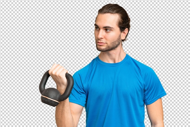 young handsome man isolated on green chroma background making weightlifting with kettlebell