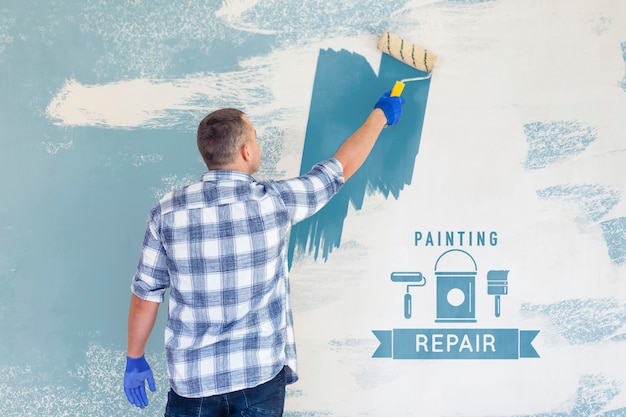 young handyman painting the wall in blue