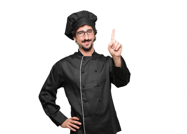 Giovane chef sorridente e guardando soddisfatto e felice, contando il numero con un dito