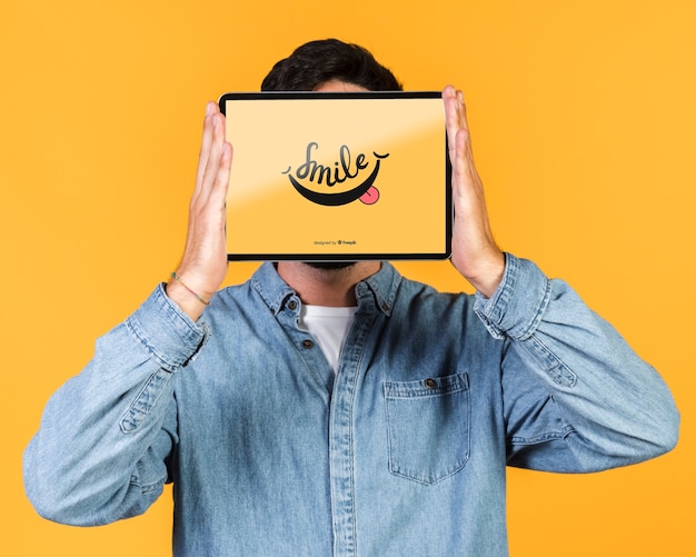 Young man covering his face with a tablet mock up