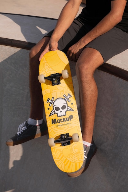 Giovane che tiene uno skateboard mock-up