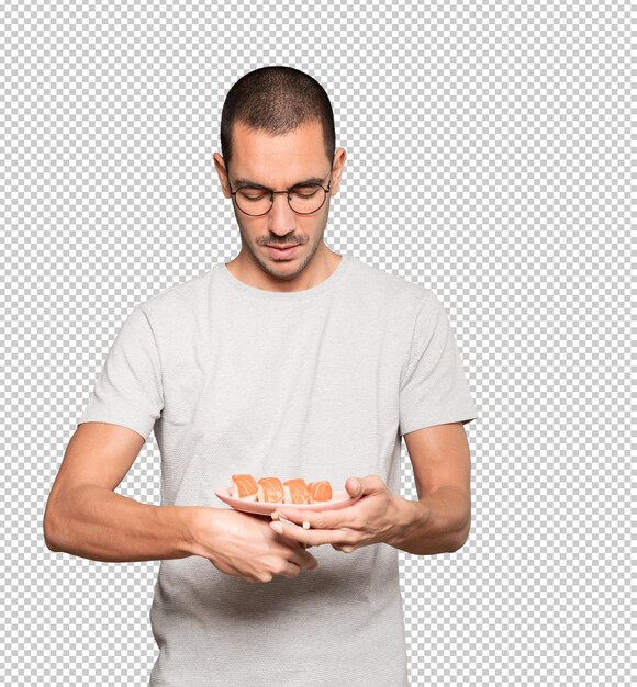 Young man using chopsticks to eat sushi