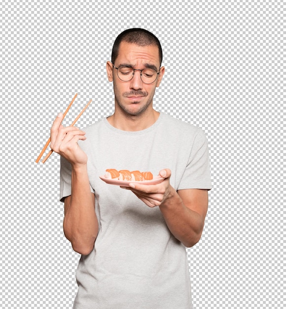 PSD young man using chopsticks to eat sushi