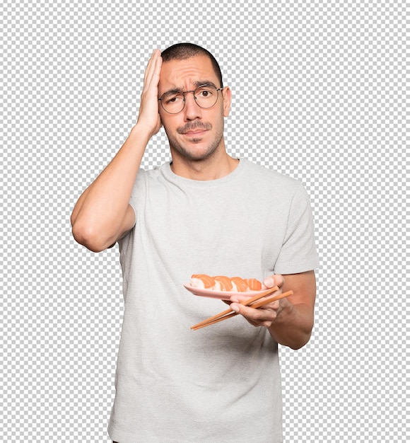 Young man using chopsticks to eat sushi