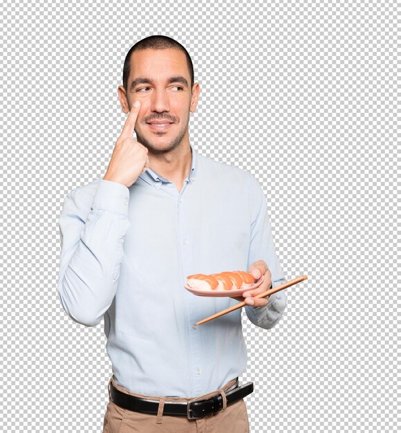 Young man using chopsticks to eat sushi