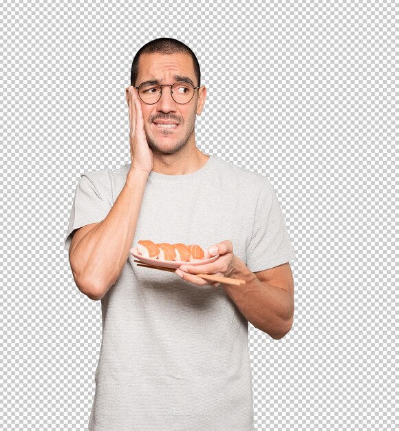 Young man using chopsticks to eat sushi