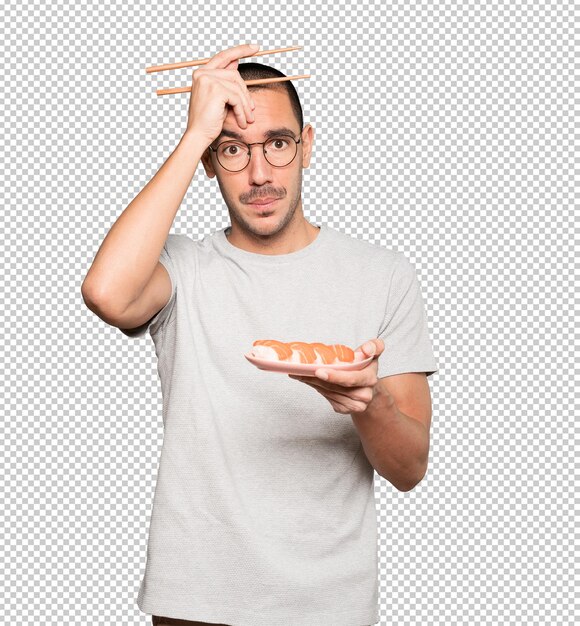 Young man using chopsticks to eat sushi