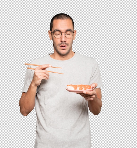 PSD young man using chopsticks to eat sushi