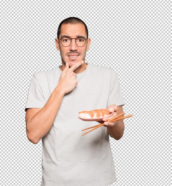 Young man using chopsticks to eat sushi