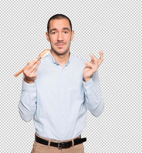 Young man using chopsticks to eat sushi