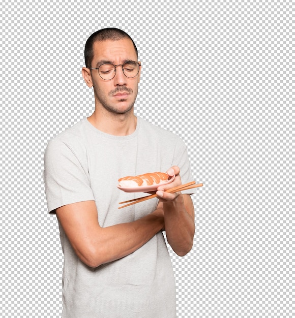 PSD young man using chopsticks to eat sushi