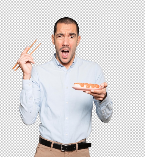 Young man using chopsticks to eat sushi