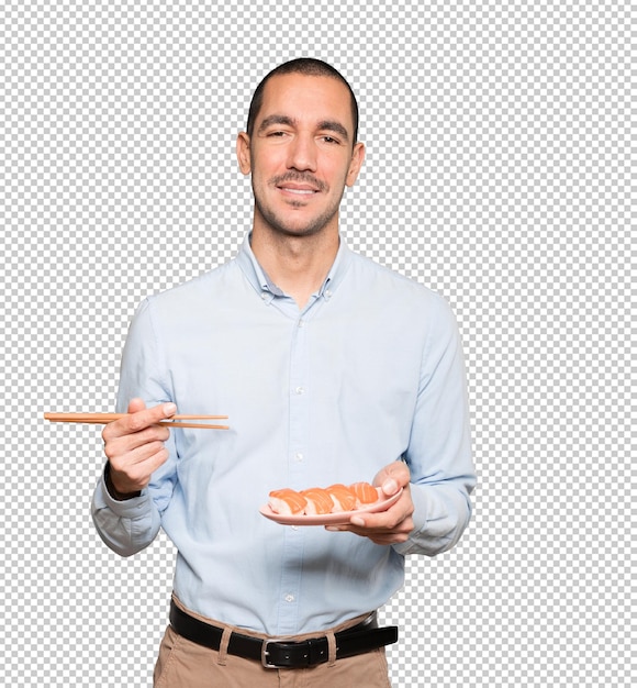 Young man using chopsticks to eat sushi