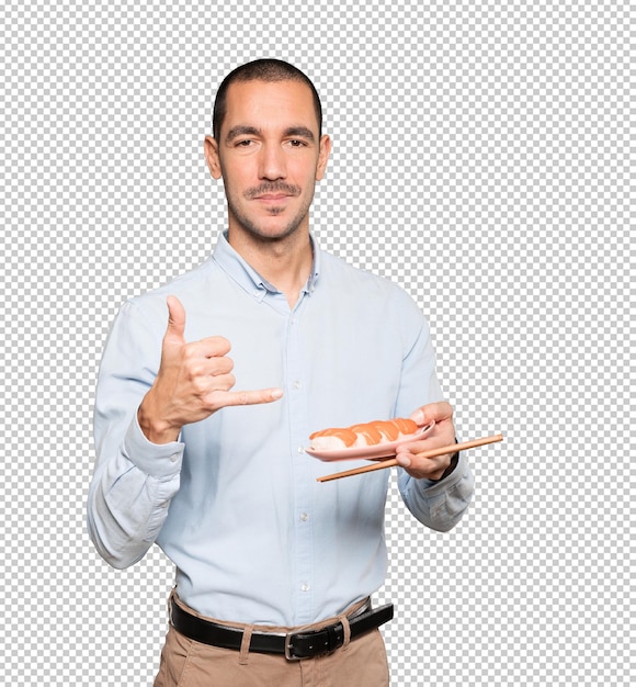 Young man using chopsticks to eat sushi