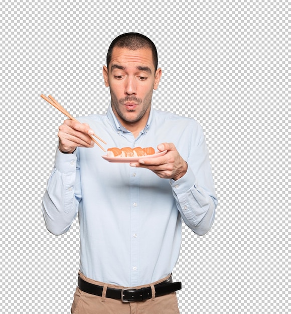 Young man using chopsticks to eat sushi