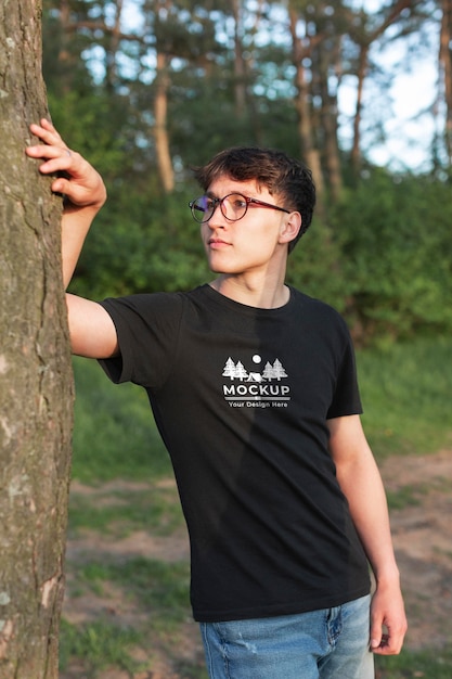 PSD young man wearing a mock-up t-shirt in the forest