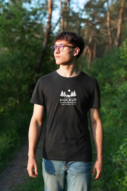 Молодой человек в макете футболки в лесу