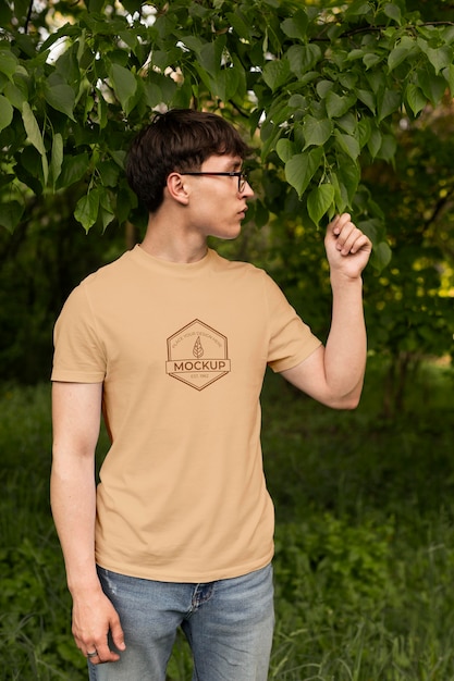 Молодой человек в макете футболки на открытом воздухе