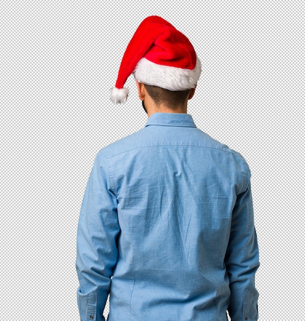 Young man wearing santa hat from behind, looking back