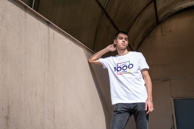 young man in white t-shirt leaning against a wall