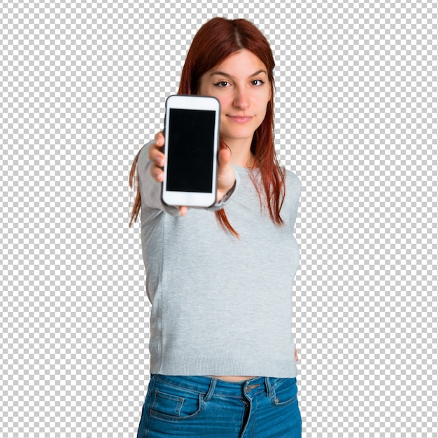 Young redhead girl looking at the camera and smiling while using the mobile