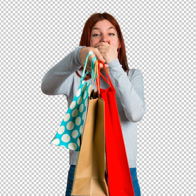 Young redhead girl surprised and holding a lot of shopping bags