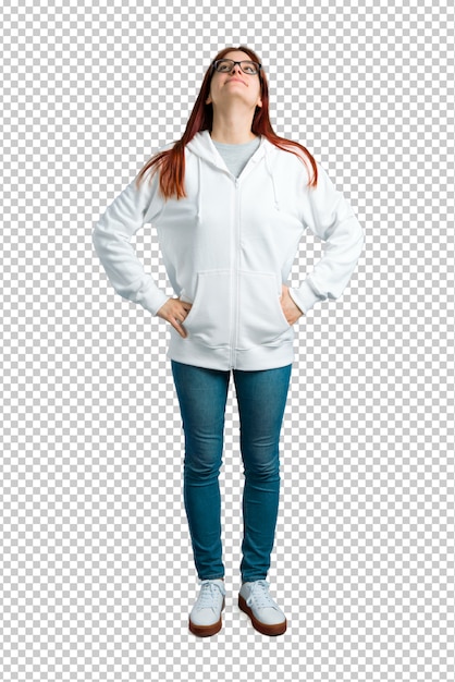 Young redhead girl in an urban white sweatshirt with glasses stand and looking up