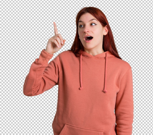 PSD young redhead girl with pink sweatshirt intending to realizes the solution while lifting a finger up