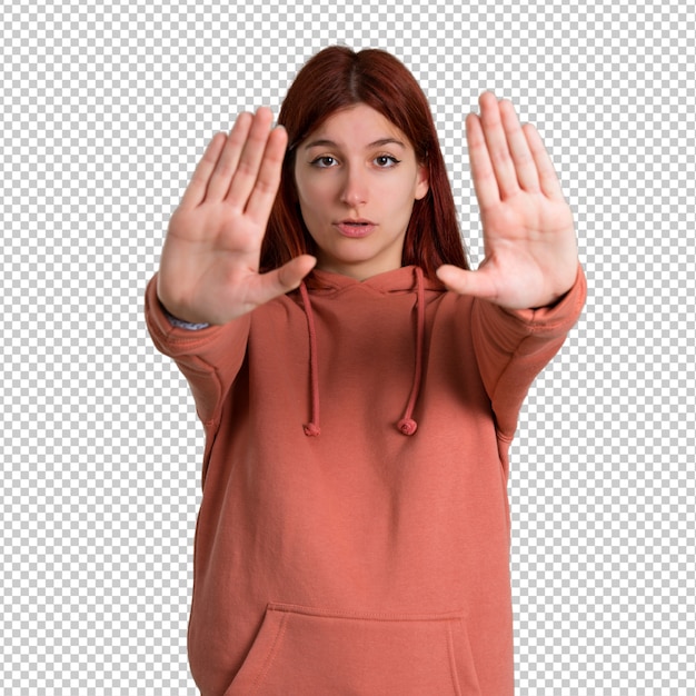 young redhead girl with pink sweatshirt making stop gesture with her hand for disappointed