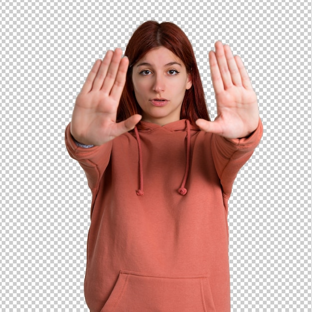 PSD young redhead girl with pink sweatshirt making stop gesture with her hand for disappointed