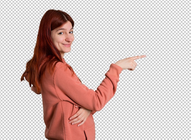 Young redhead girl with pink sweatshirt pointing finger to the side