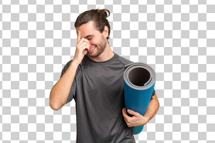 PSD young sport man going to yoga classes while holding a mat over isolated background laughing